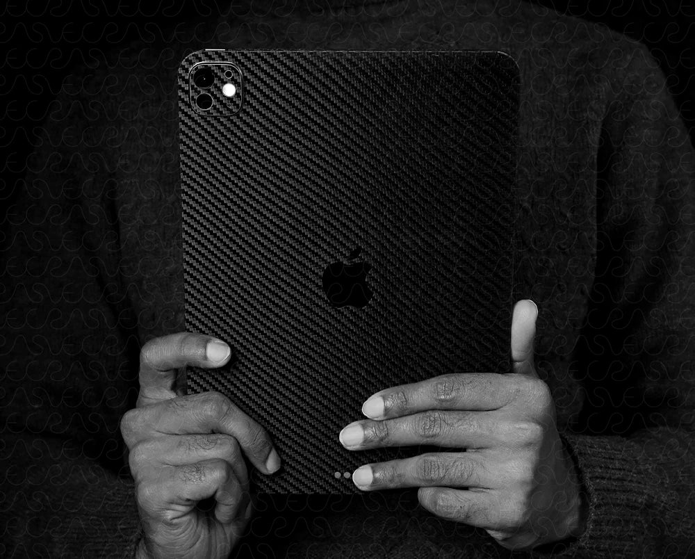 Person holding a black carbon fiber texture phone case with an Apple logo.